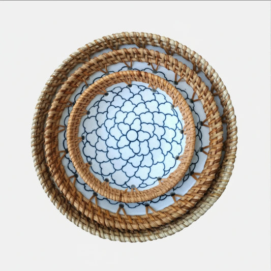 Indigo Cloud ceramic bowl set of three with hand-woven rattan rims stacked on a white marble background.