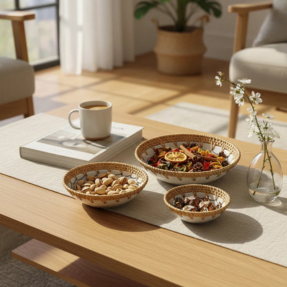 Dragonfly Drift rattan-rim ceramic bowls styled on a centre table with snacks and a cup, showing three bowl sizes
