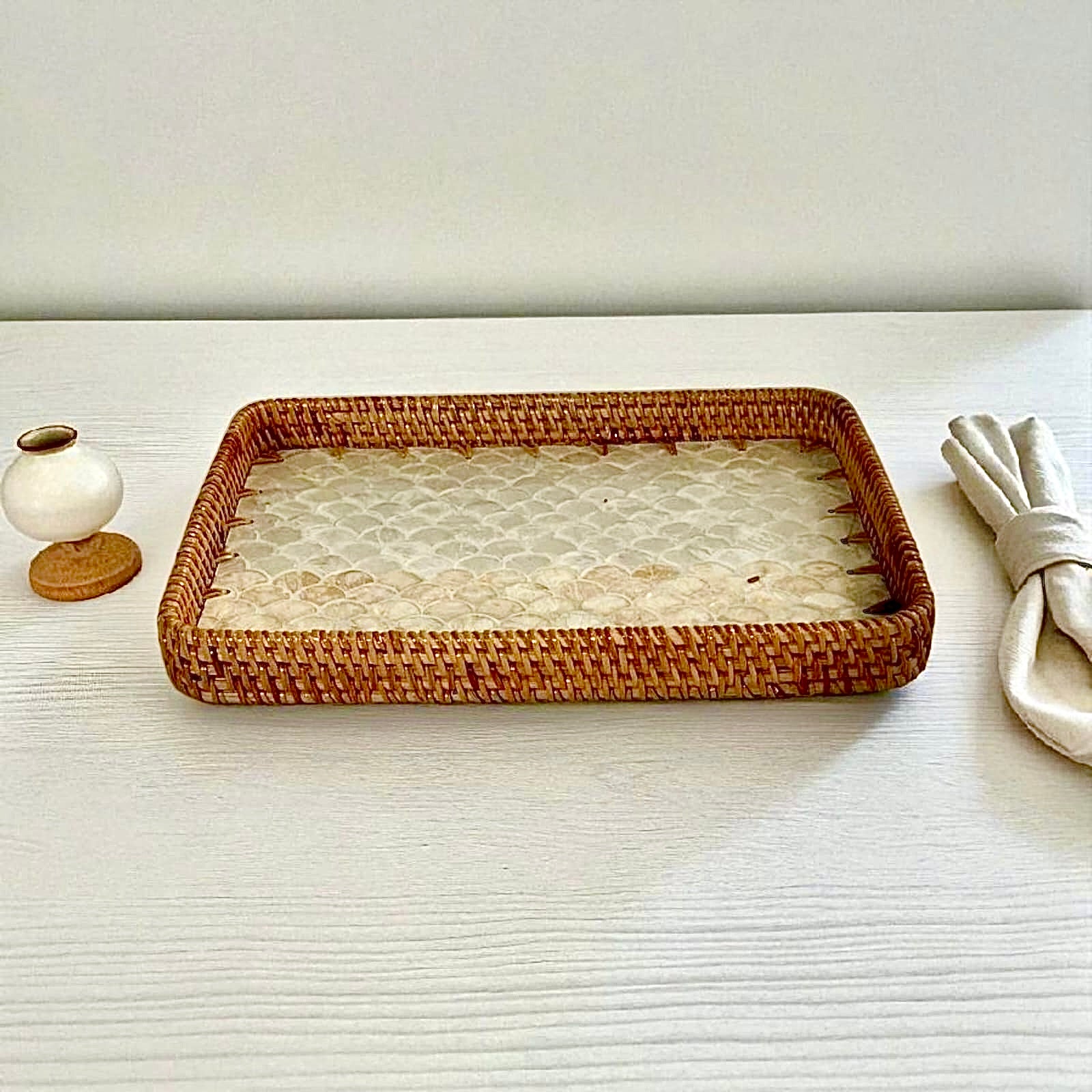 Rectangular rattan tray with mother-of-pearl base styled with cups and decor