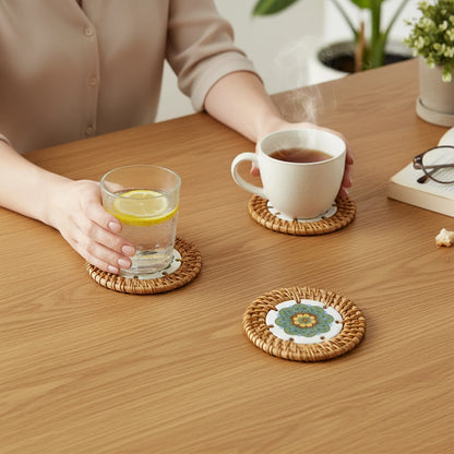 Meadow Mandala ceramic rattan coaster on wooden table with cup—protects surface from water rings and heat marks.