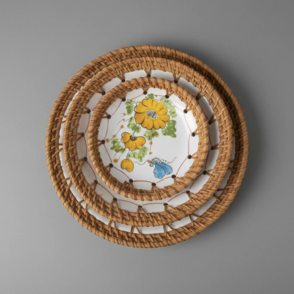 Set of three Marigold Bloom ceramic bowls with hand-woven rattan rims on a grey background