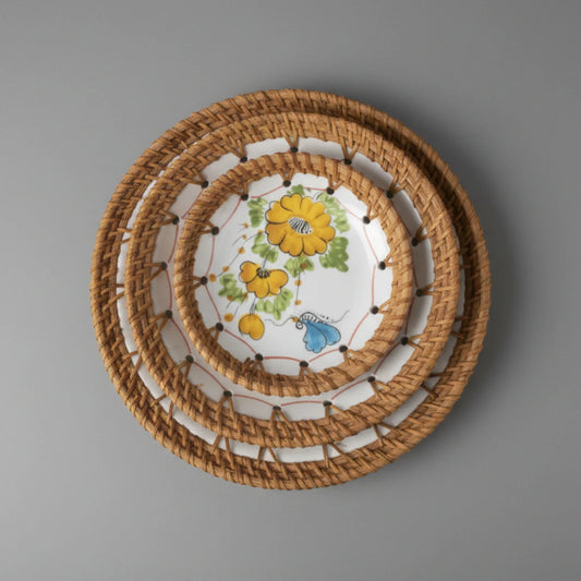Set of three Marigold Bloom ceramic bowls with hand-woven rattan rims on a grey background