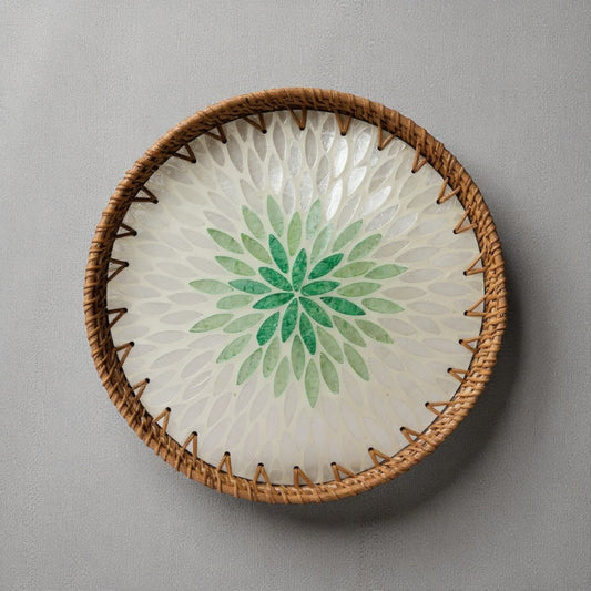 Green lotus mother-of-pearl mosaic tray with rattan rim on neutral fabric background